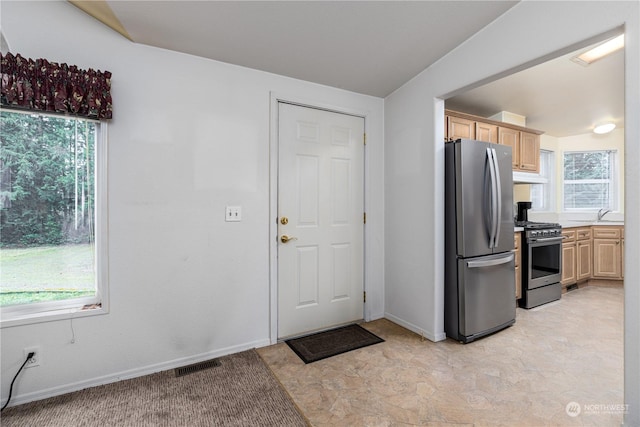 kitchen featuring sink, stainless steel appliances, vaulted ceiling, and light brown cabinets