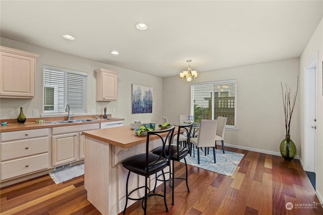 kitchen featuring sink, an inviting chandelier, hanging light fixtures, a kitchen island, and dark hardwood / wood-style flooring