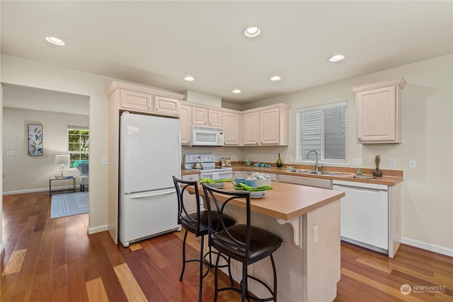 kitchen with white appliances, a center island, dark wood-type flooring, sink, and white cabinetry