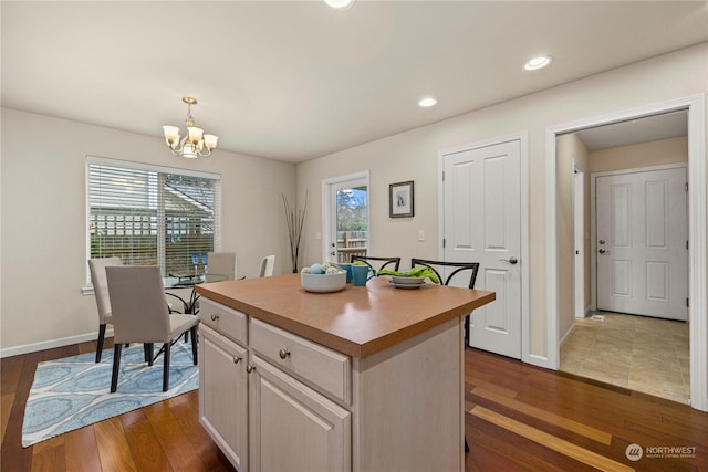 kitchen featuring dark wood-type flooring, a chandelier, a center island, decorative light fixtures, and white cabinetry