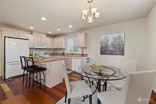 kitchen featuring white appliances, hanging light fixtures, dark hardwood / wood-style floors, an inviting chandelier, and white cabinetry