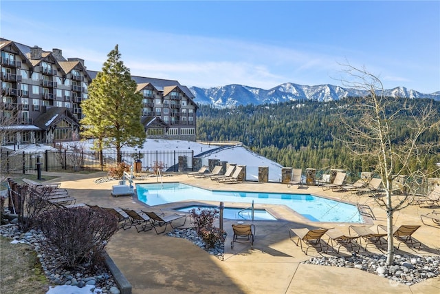 view of pool featuring a mountain view, a patio, and a hot tub