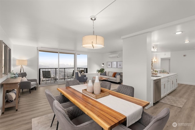 dining space featuring expansive windows, light hardwood / wood-style floors, an AC wall unit, and sink