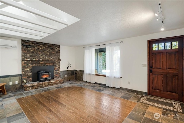 entryway with rail lighting, an AC wall unit, and a textured ceiling