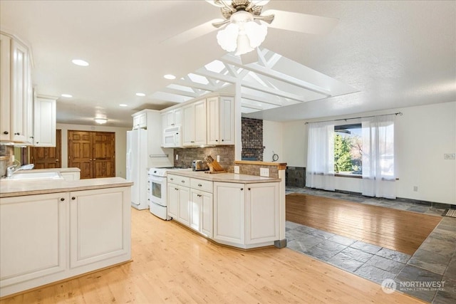 kitchen featuring white cabinetry, white appliances, kitchen peninsula, and sink