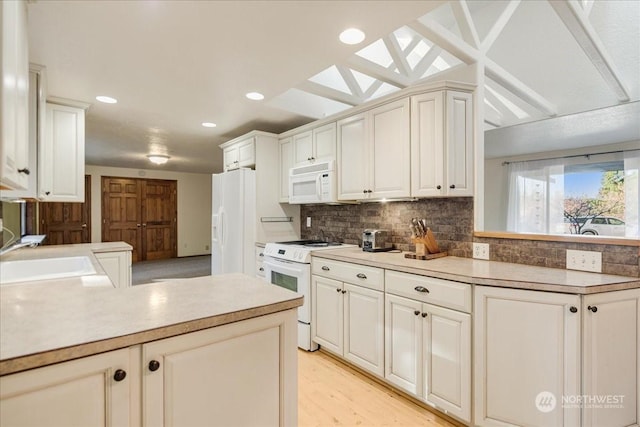 kitchen with sink, backsplash, white appliances, light hardwood / wood-style floors, and white cabinets