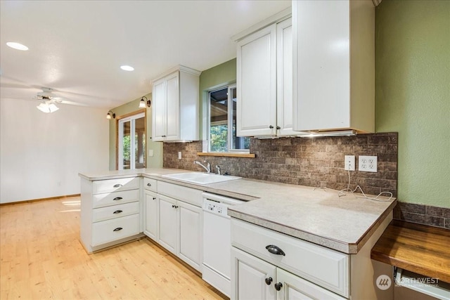 kitchen featuring dishwasher, sink, white cabinets, kitchen peninsula, and light hardwood / wood-style flooring