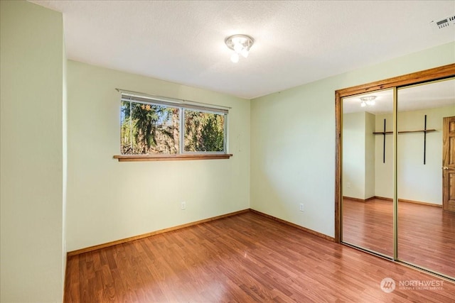 unfurnished bedroom with hardwood / wood-style flooring, a closet, and a textured ceiling