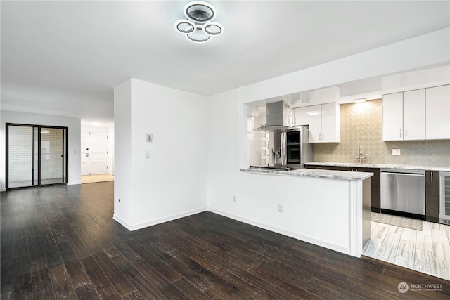 kitchen with wood finished floors, a sink, white cabinetry, dishwasher, and island exhaust hood