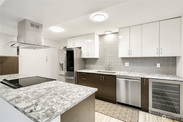 kitchen featuring beverage cooler, island range hood, white cabinets, appliances with stainless steel finishes, and a sink