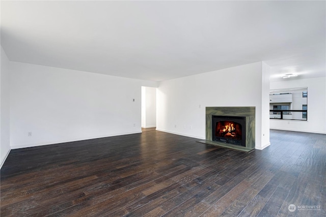 unfurnished living room with dark wood-style floors, a premium fireplace, and baseboards