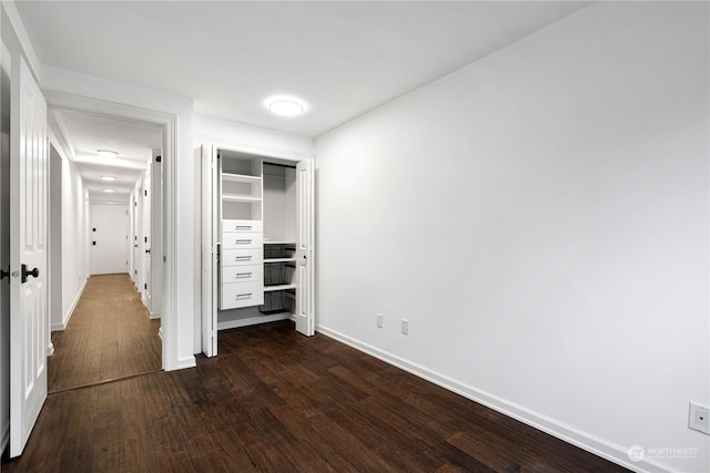 unfurnished bedroom with a closet, dark wood finished floors, and baseboards