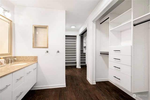 bathroom featuring a walk in closet, wood finished floors, vanity, and baseboards