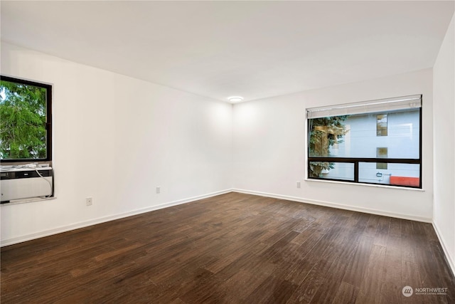 spare room featuring baseboards and dark wood-type flooring