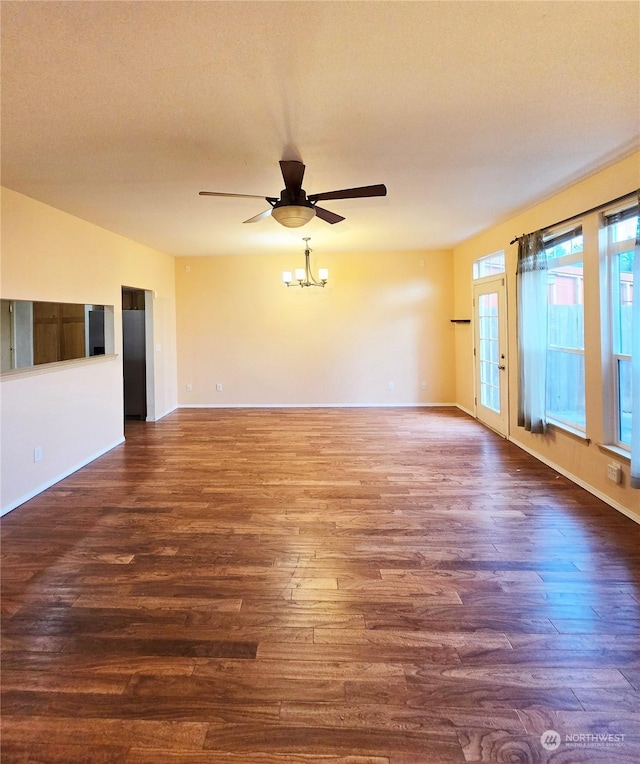 unfurnished room featuring ceiling fan with notable chandelier and dark hardwood / wood-style floors