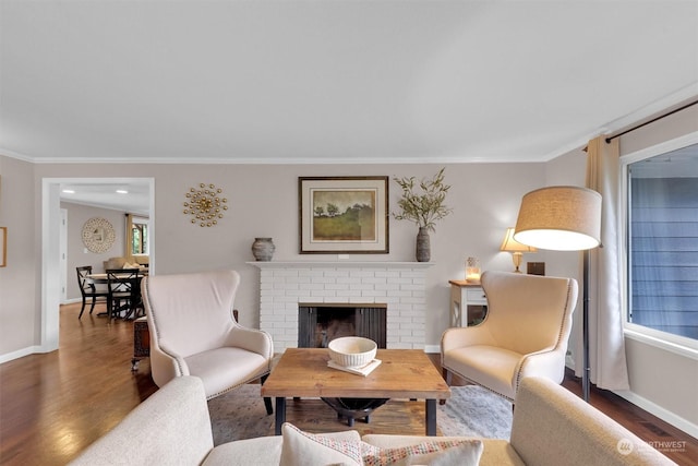 living room with dark hardwood / wood-style flooring, a brick fireplace, and crown molding