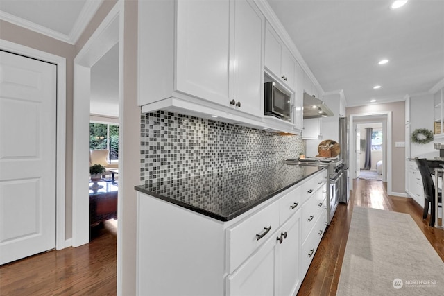 kitchen with backsplash, appliances with stainless steel finishes, dark hardwood / wood-style floors, and white cabinetry