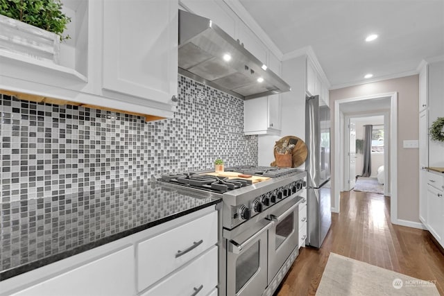 kitchen featuring white cabinets, appliances with stainless steel finishes, wall chimney exhaust hood, and decorative backsplash