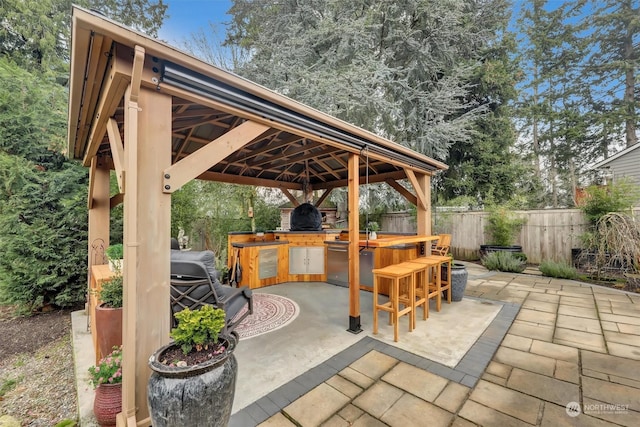 view of patio with a gazebo, an outdoor kitchen, and exterior bar