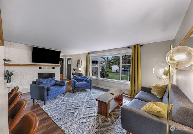 living room with a brick fireplace and hardwood / wood-style flooring