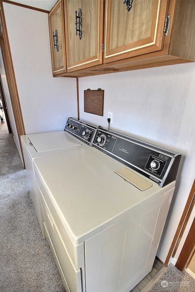 clothes washing area with washer and dryer, cabinets, and carpet flooring