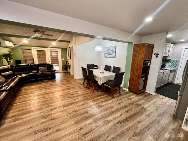 dining space with light wood-type flooring, ceiling fan, and a wall mounted air conditioner