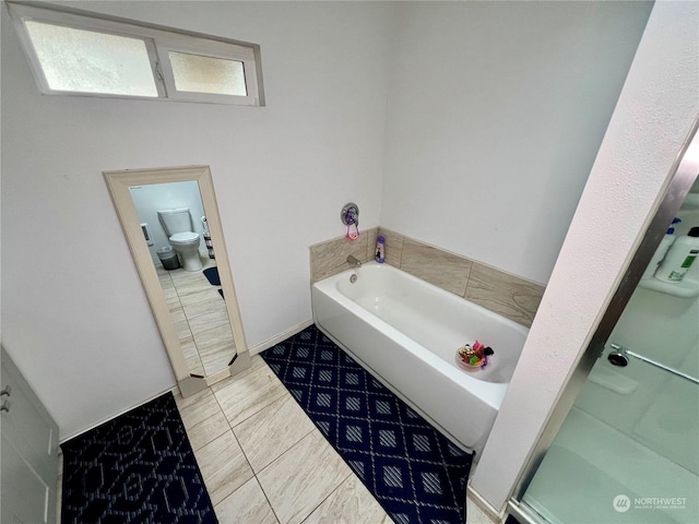 bathroom with toilet, tile patterned floors, plenty of natural light, and a bath