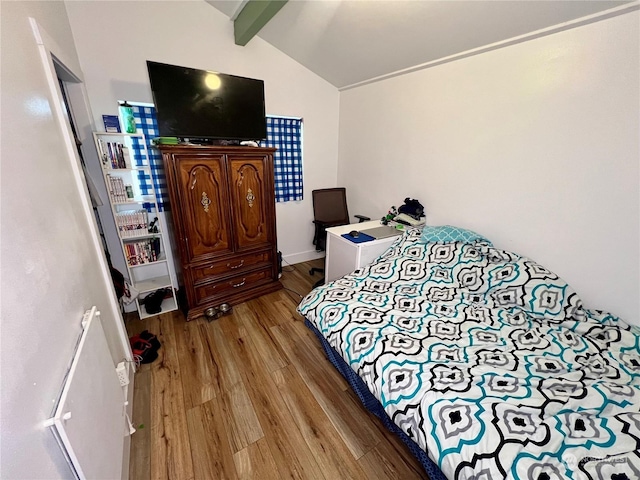 bedroom with light hardwood / wood-style floors and vaulted ceiling with beams