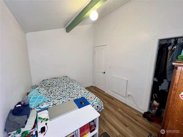 bedroom with a closet, beamed ceiling, and wood-type flooring