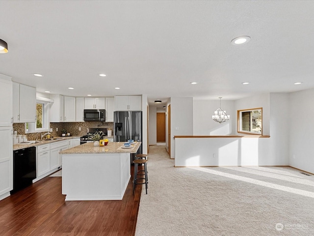 kitchen with appliances with stainless steel finishes, white cabinetry, backsplash, a center island, and decorative light fixtures