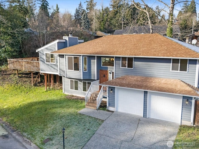 bi-level home with a garage, a deck, and a front lawn