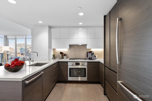 kitchen with stainless steel appliances, sink, white cabinets, kitchen peninsula, and dark brown cabinetry