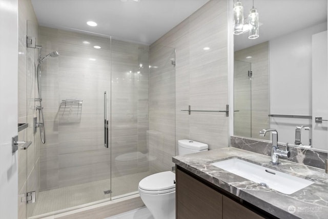 bathroom featuring toilet, an enclosed shower, vanity, and tile walls