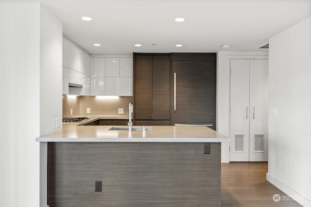 kitchen featuring sink, white cabinetry, tasteful backsplash, kitchen peninsula, and dark hardwood / wood-style flooring