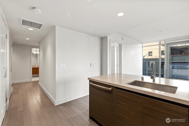 kitchen with dishwasher, light hardwood / wood-style floors, expansive windows, and sink