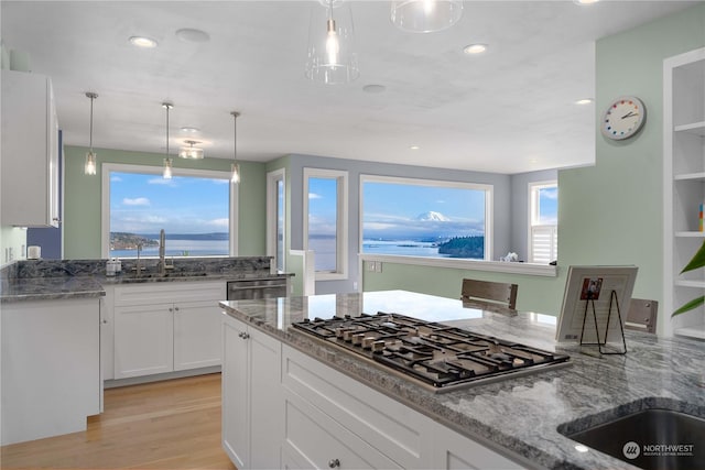 kitchen featuring hanging light fixtures, sink, white cabinetry, light stone counters, and stainless steel appliances