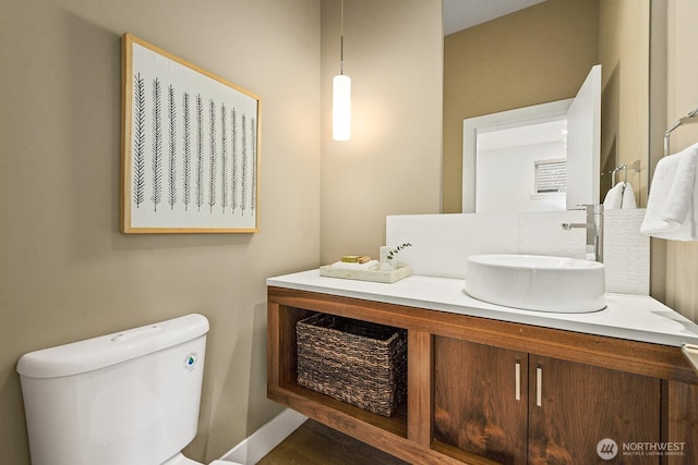 bathroom with baseboards, vanity, and toilet