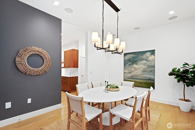 dining space featuring light wood-type flooring, baseboards, and a notable chandelier