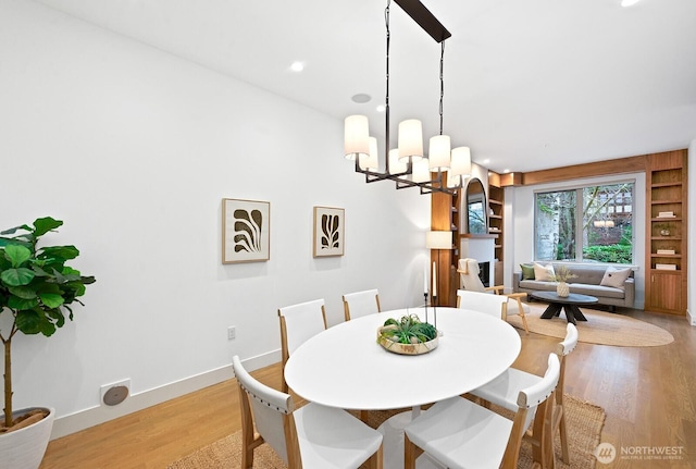 dining space with baseboards, built in features, an inviting chandelier, light wood-style floors, and recessed lighting