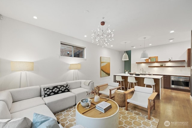 living area featuring light wood finished floors, an inviting chandelier, and recessed lighting