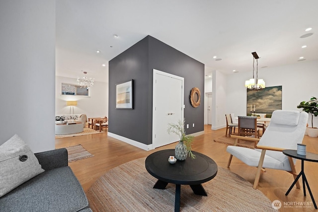 living area featuring recessed lighting, light wood-style flooring, baseboards, and an inviting chandelier