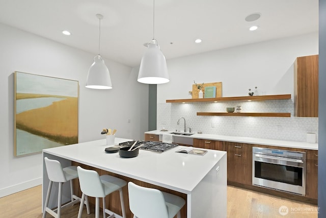 kitchen featuring pendant lighting, open shelves, light countertops, appliances with stainless steel finishes, and a kitchen island