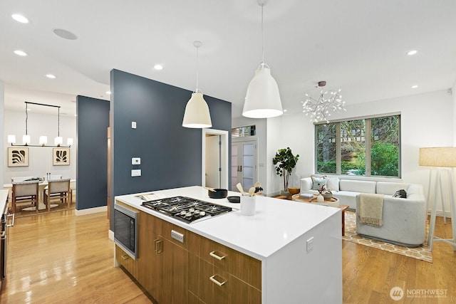 kitchen featuring a kitchen island, brown cabinets, open floor plan, light countertops, and light wood-type flooring