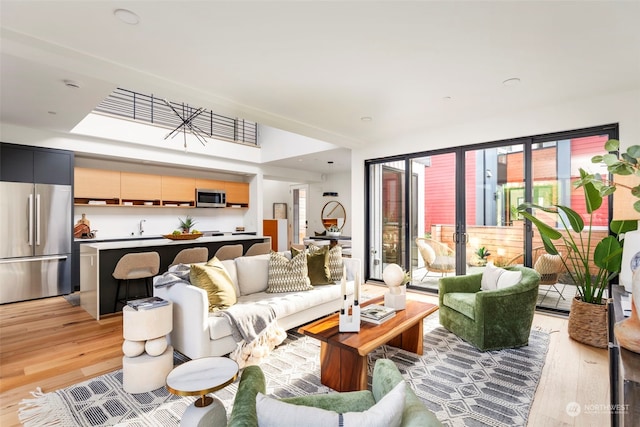 living room featuring sink, light wood-type flooring, and a wealth of natural light