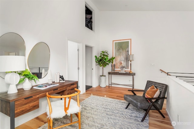 office with a towering ceiling and hardwood / wood-style floors