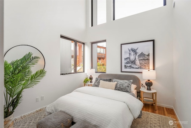 bedroom with a towering ceiling and hardwood / wood-style floors