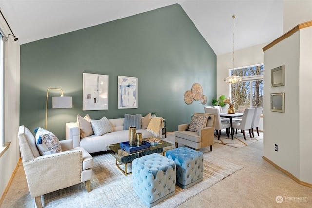 living room with high vaulted ceiling, light colored carpet, and a chandelier