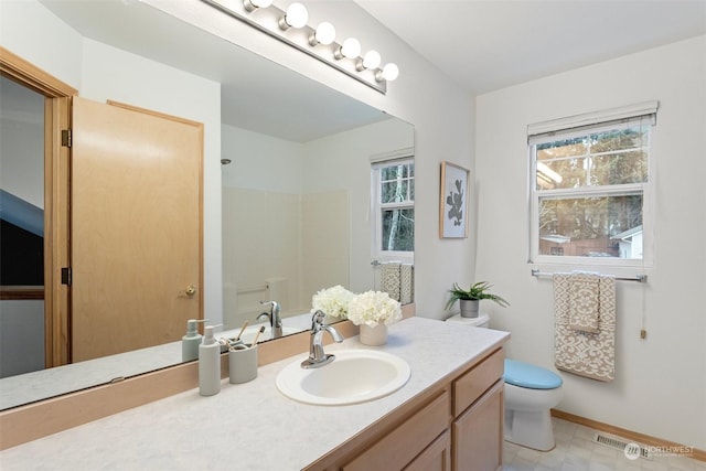 bathroom featuring toilet, vanity, a healthy amount of sunlight, and walk in shower