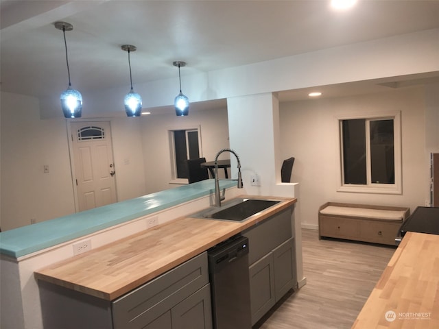 kitchen featuring butcher block counters, dishwasher, sink, and decorative light fixtures