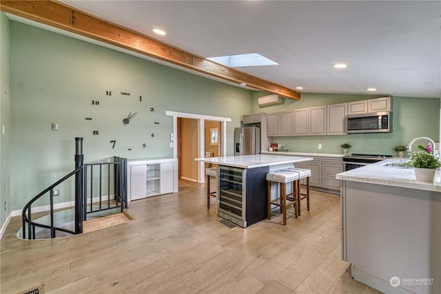 kitchen featuring light hardwood / wood-style flooring, a kitchen bar, gray cabinetry, appliances with stainless steel finishes, and sink